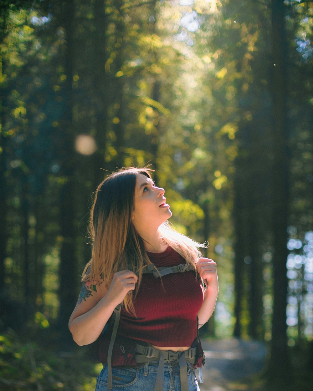 woman in red sleeveless top standing near green trees during daytime