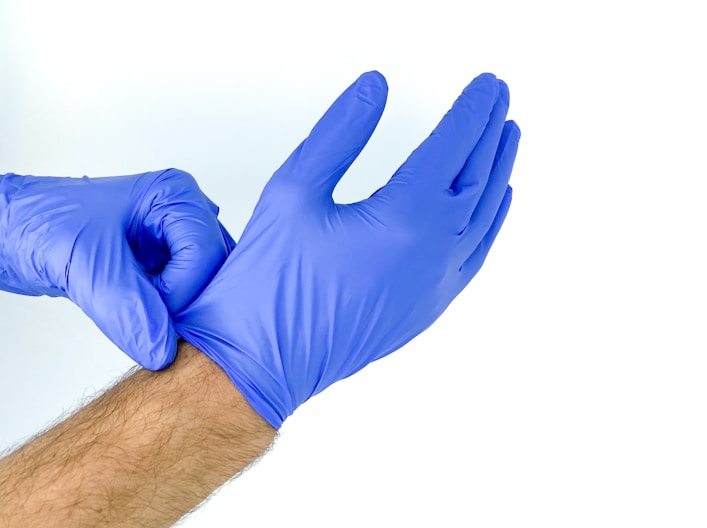 A person wearing a pair of blue nitrile gloves