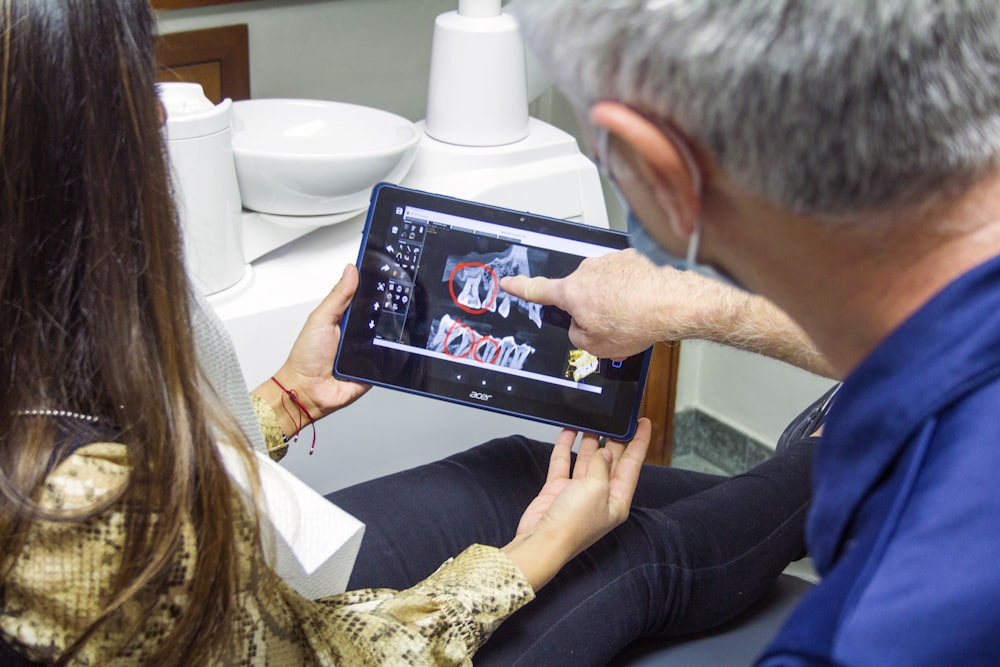 mulher em jeans azuis que seguram o computador tablet preto