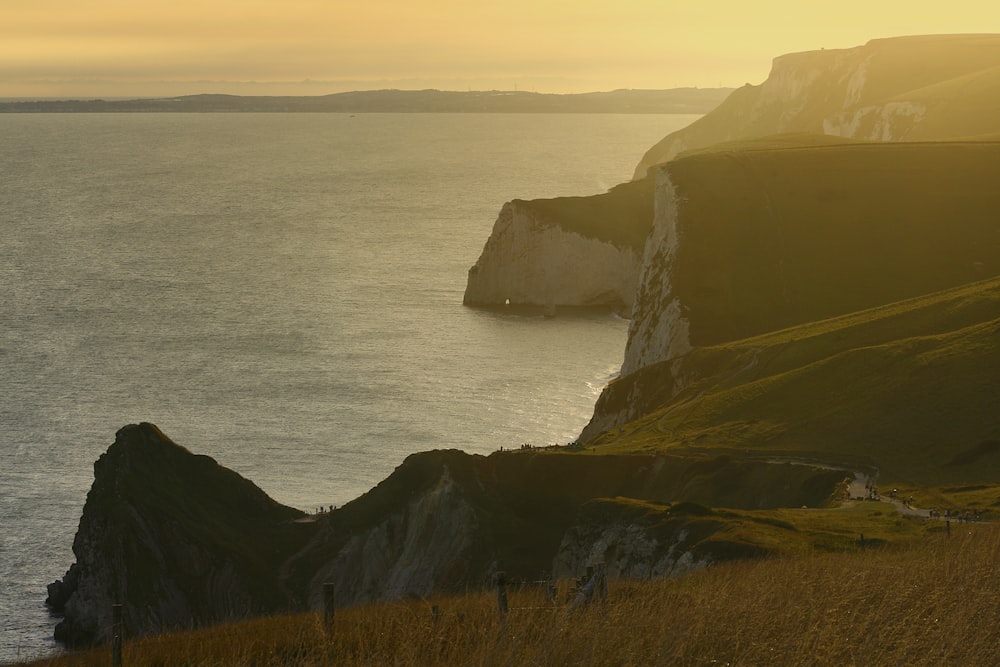 green and brown mountain beside sea during daytime