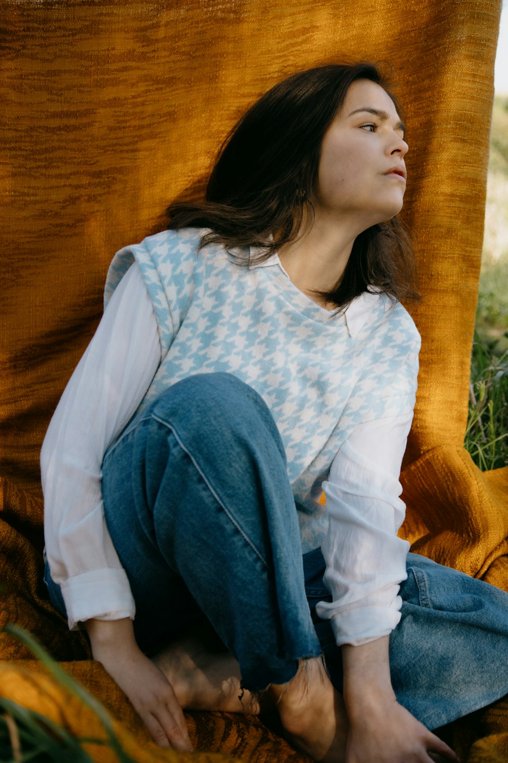 woman in white and blue long sleeve shirt and blue denim jeans sitting on brown wooden