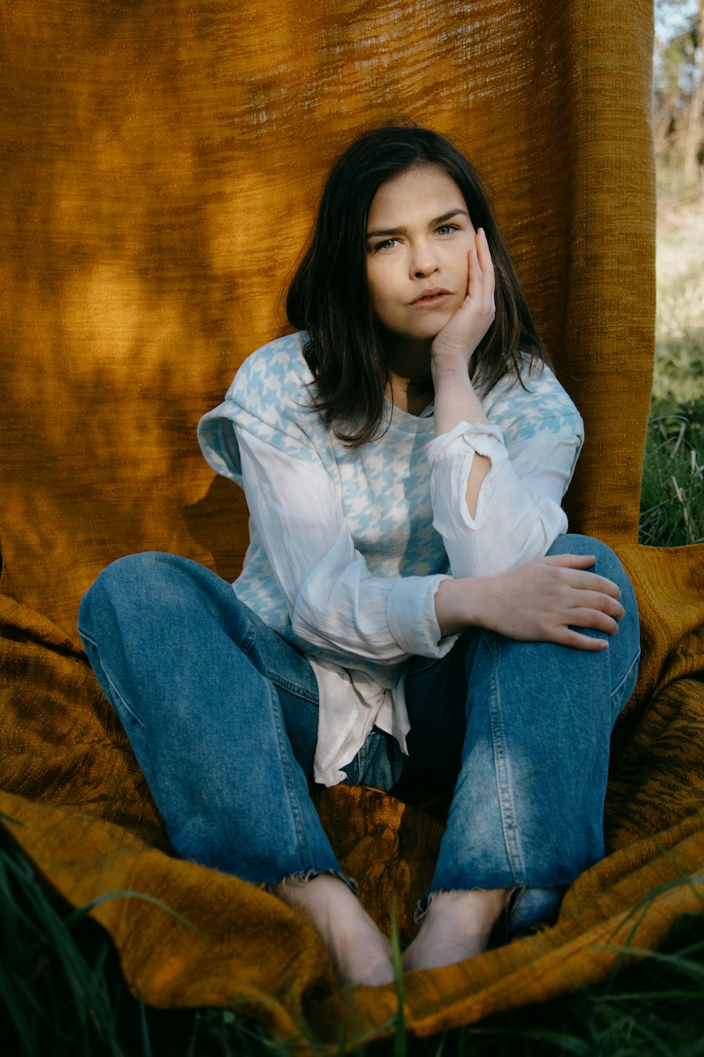 woman in white dress shirt and blue denim jeans sitting on brown sofa