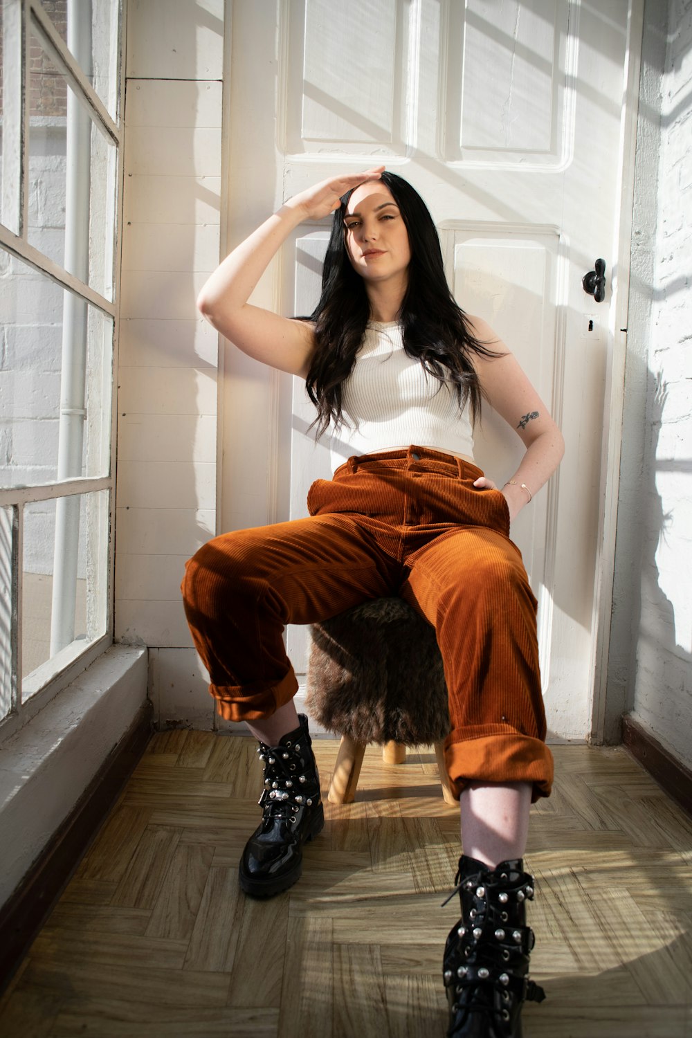 woman in white tank top and orange pants sitting on white staircase