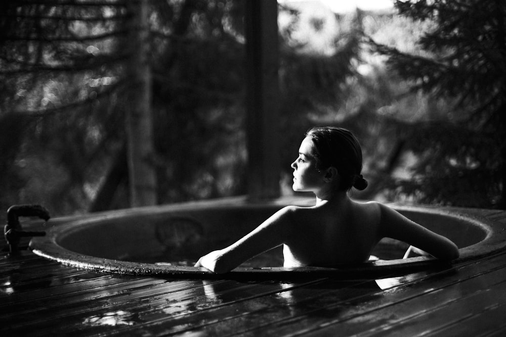 grayscale photo of topless woman sitting on wooden dock