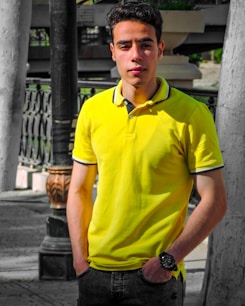 man in yellow polo shirt standing near white wall during daytime