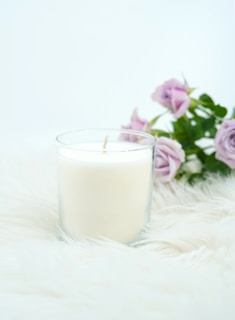 A white cleansing candle surrounded by sage and rose petals, ready for a spiritual ritual.