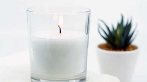 white candle in clear glass candle holder