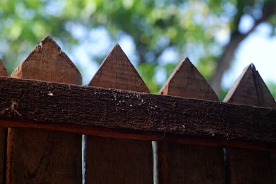 A close-up of a wooden fence bordering a quiet, open field.