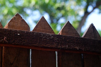 A close-up of a wooden fence bordering a quiet, open field.
