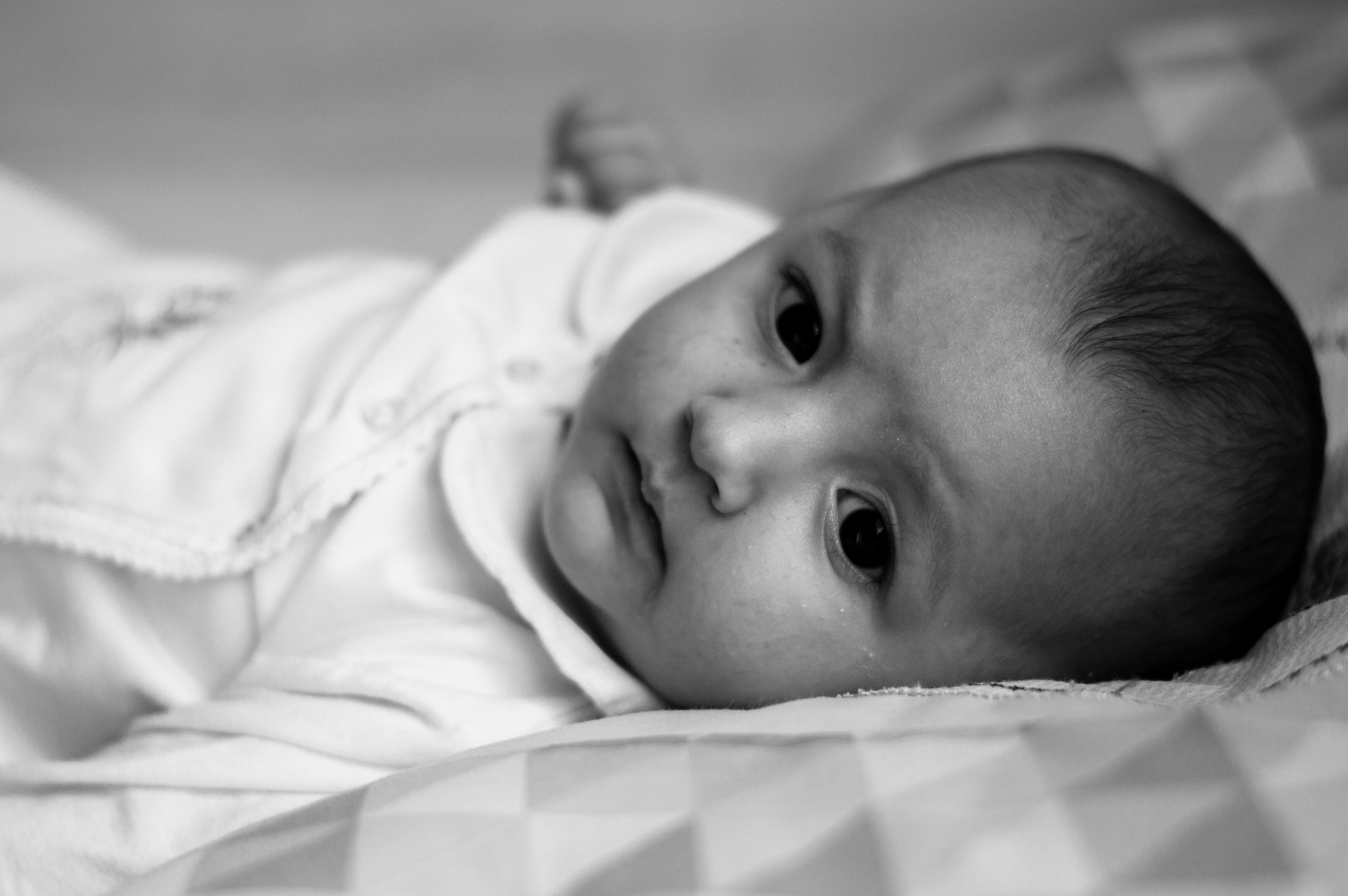 baby in white shirt lying on bed