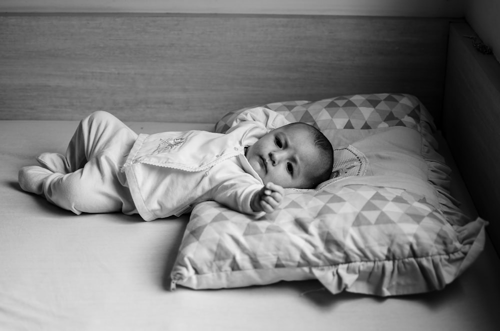 grayscale photo of baby lying on bed