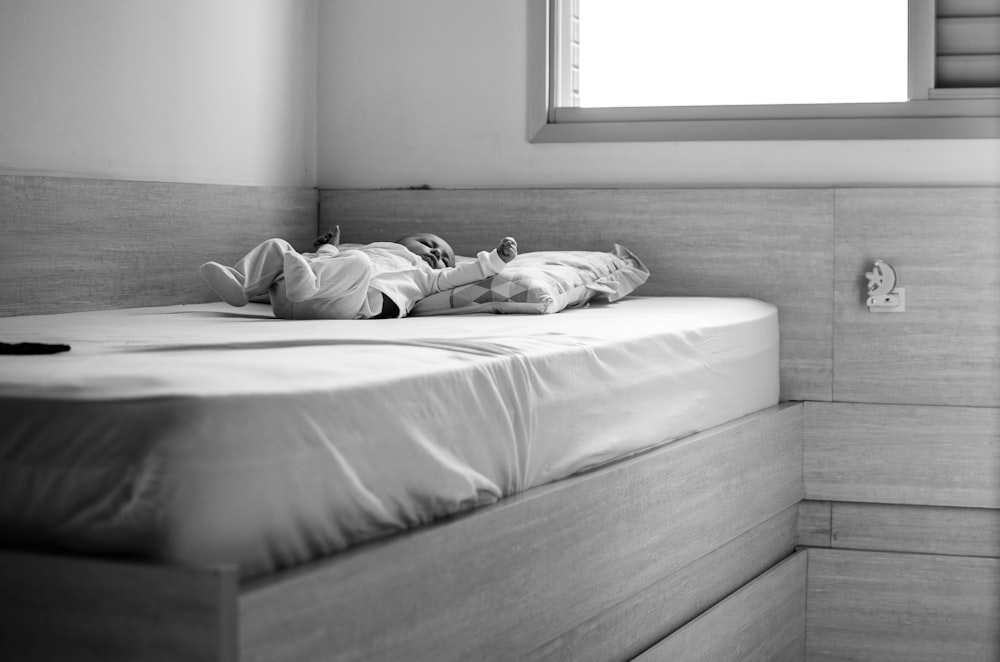 grayscale photo of woman lying on bed