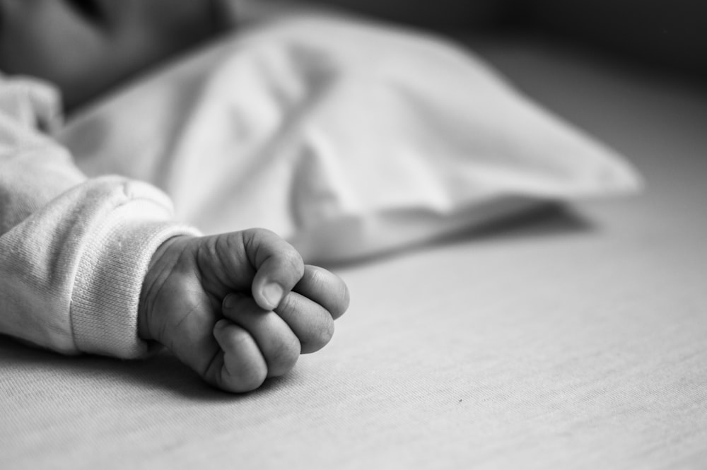 grayscale photo of babys feet on wooden table