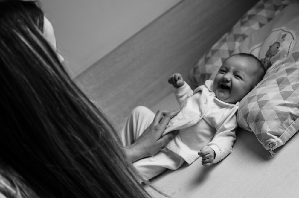 grayscale photo of woman and child lying on bed