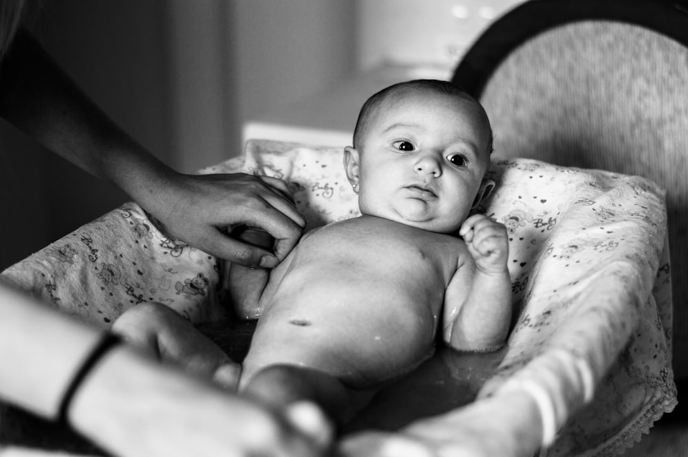 grayscale photo of baby lying on bed