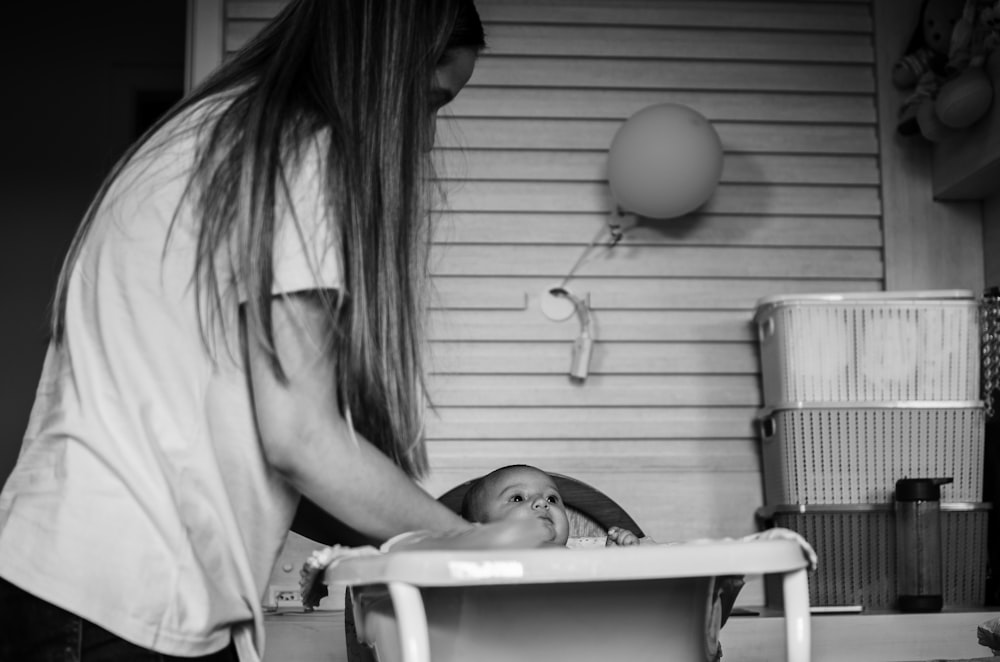 woman in white tank top carrying baby in white shirt