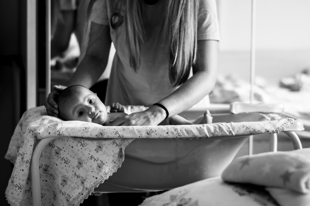 woman in white shirt carrying baby in bathtub