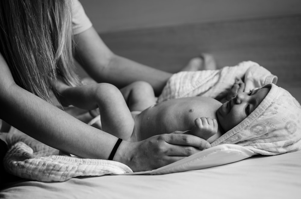 grayscale photo of woman in tank top lying on bed