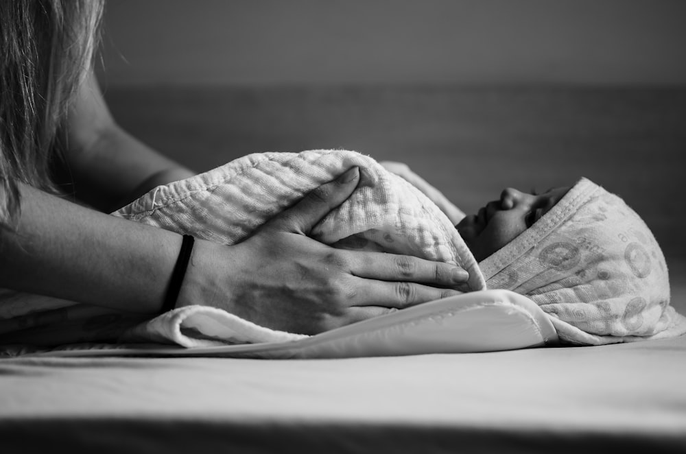 grayscale photo of woman lying on bed