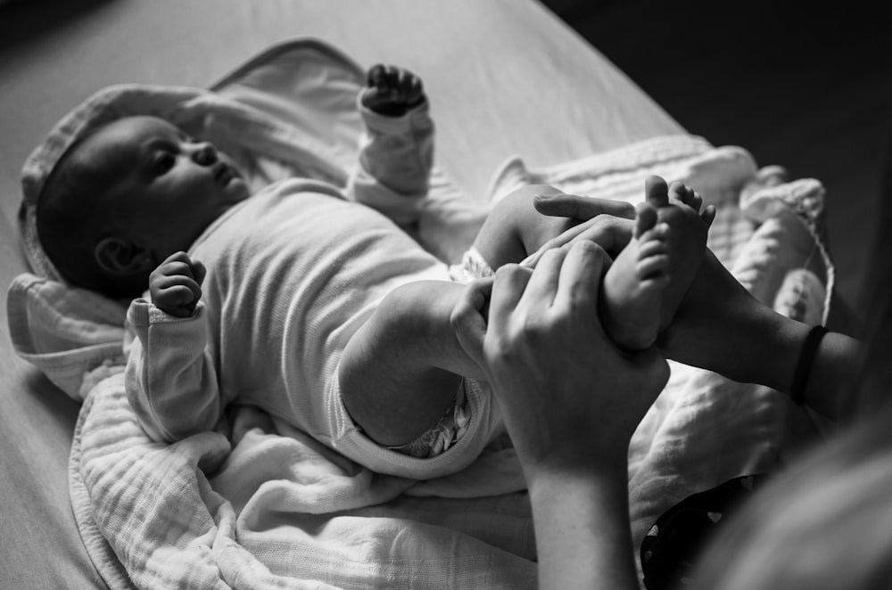 grayscale photo of baby lying on bed