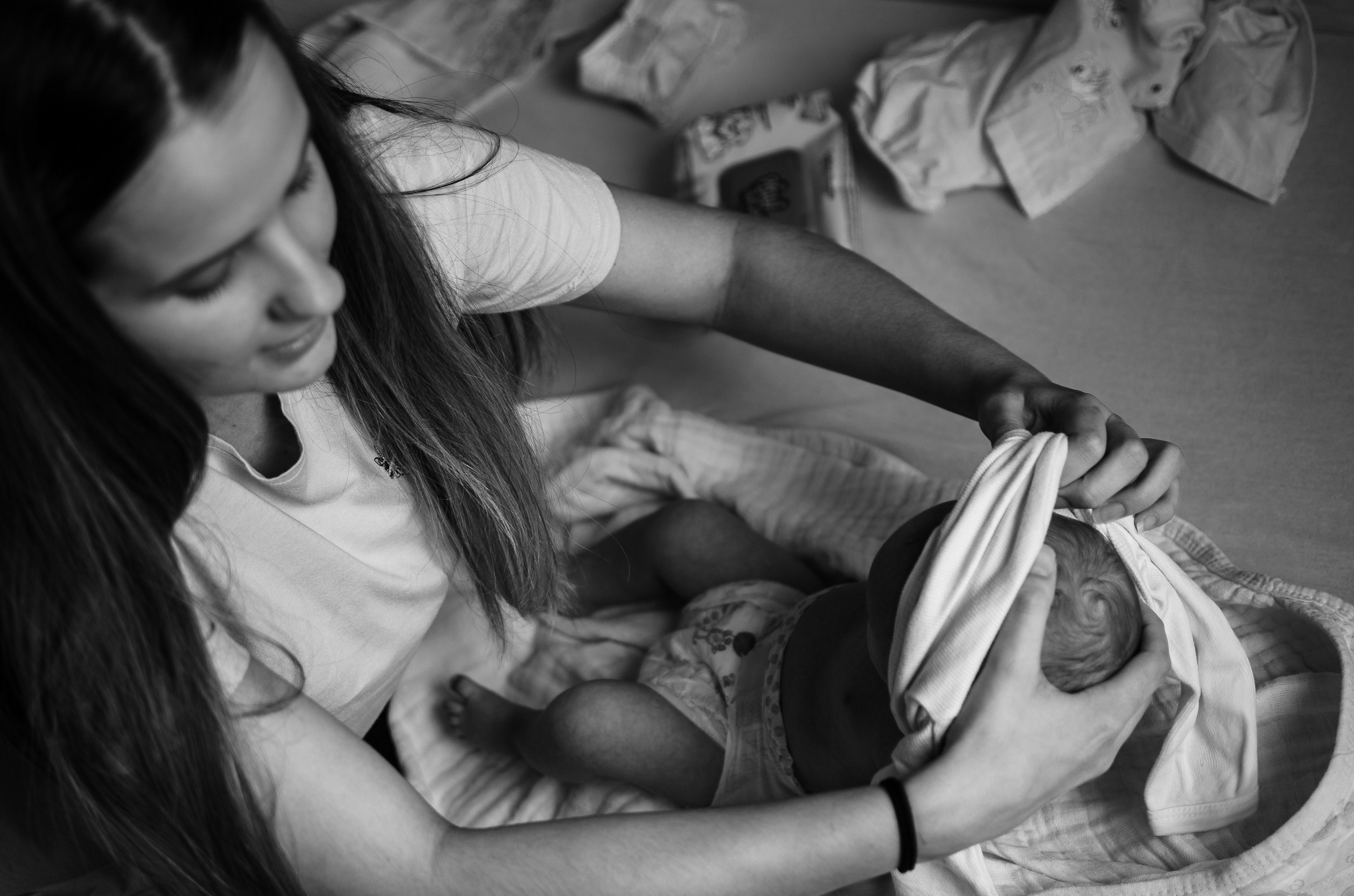 woman in white t-shirt carrying baby in grayscale photography