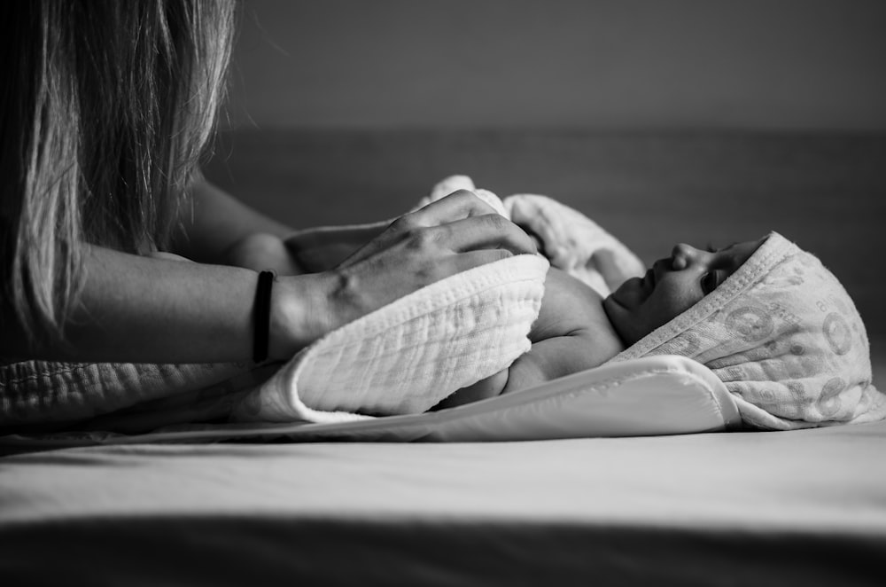 grayscale photo of woman in black and white stripe t-shirt lying on bed