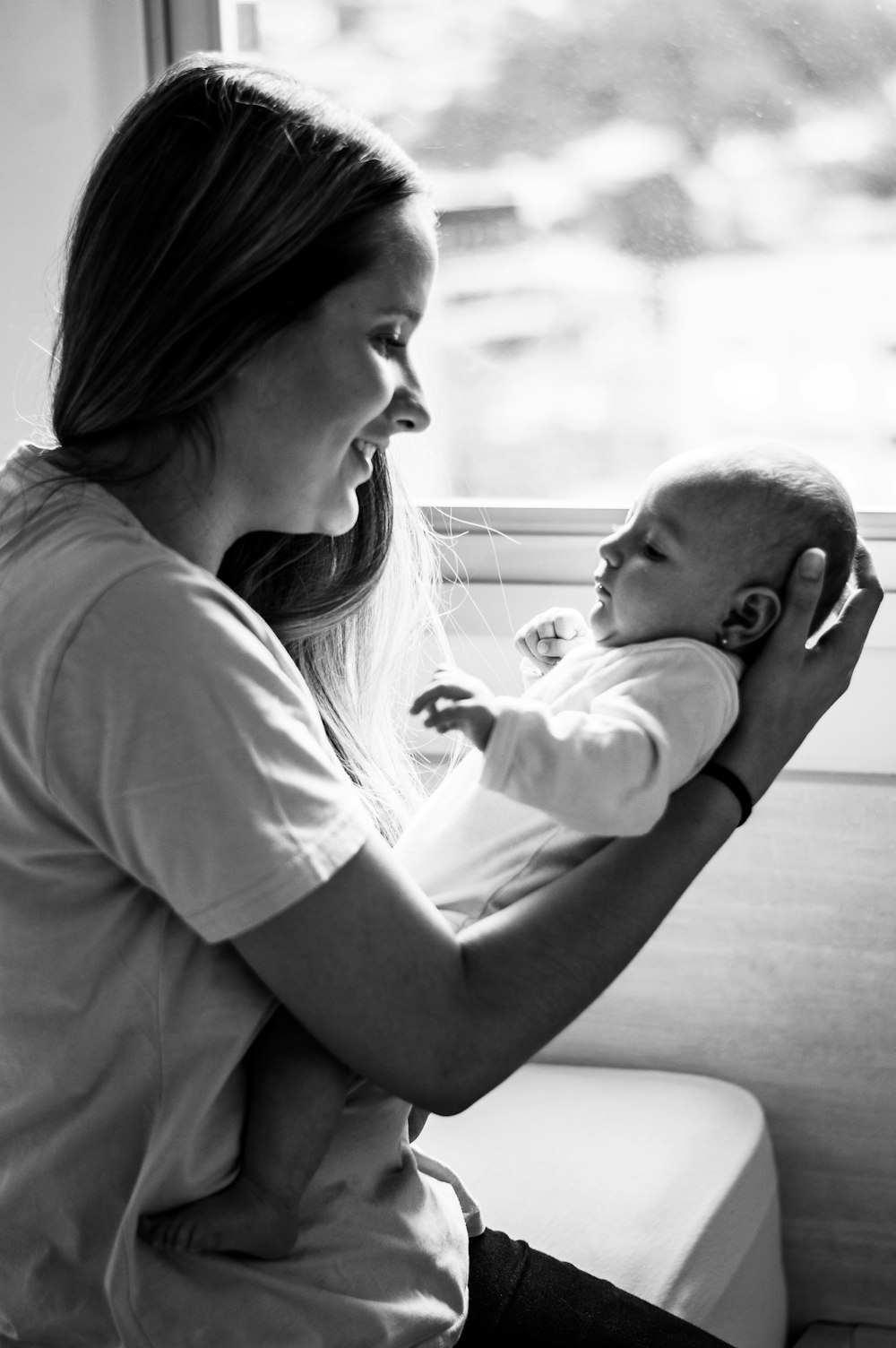 grayscale photo of woman in t-shirt carrying baby