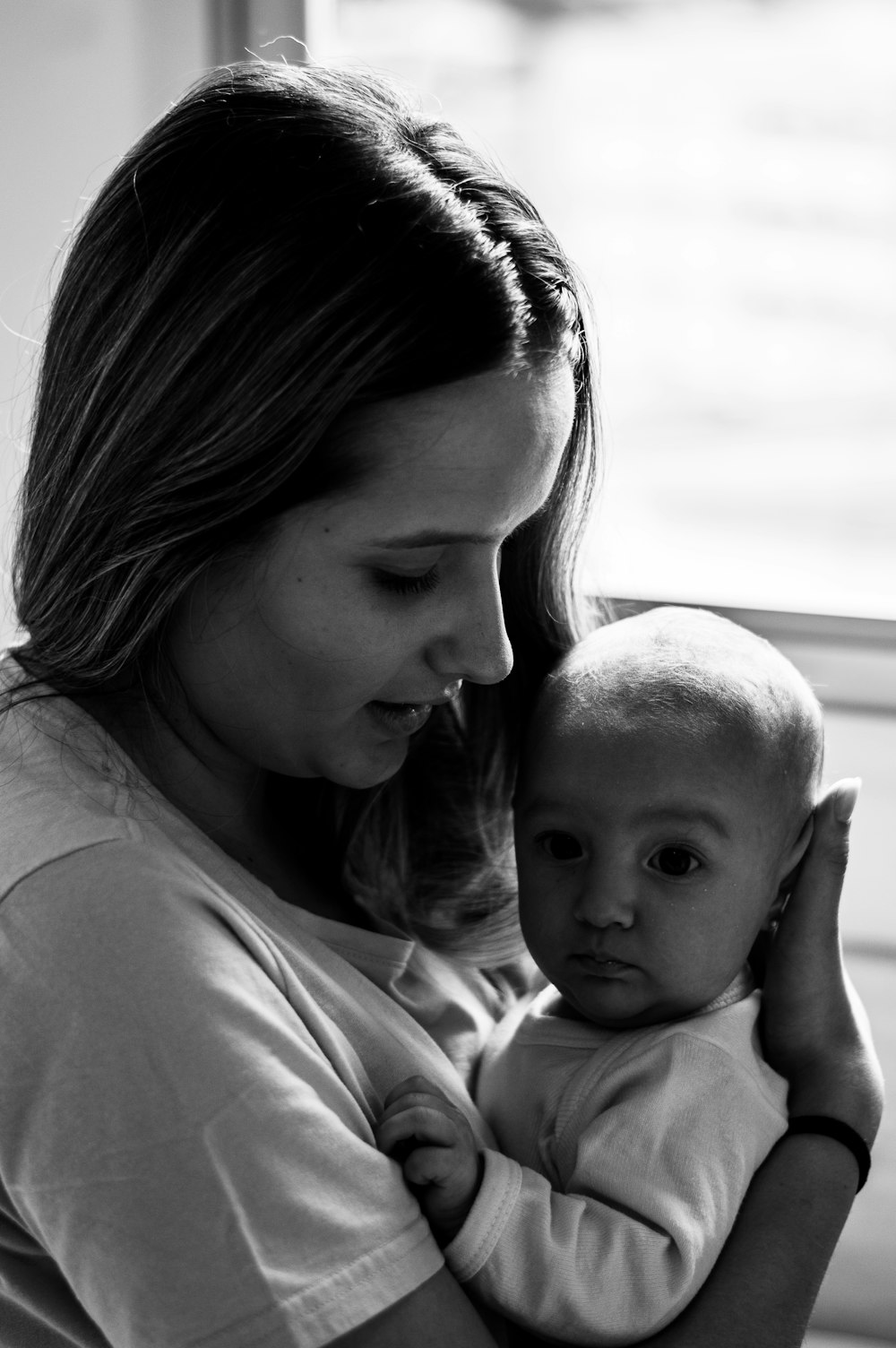 woman in white shirt carrying baby in grayscale photography