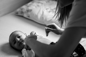 woman in white shirt holding baby on bed