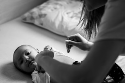 woman in white shirt holding baby on bed