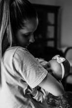 grayscale photo of woman in t-shirt carrying baby