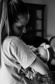 grayscale photo of woman in t-shirt carrying baby
