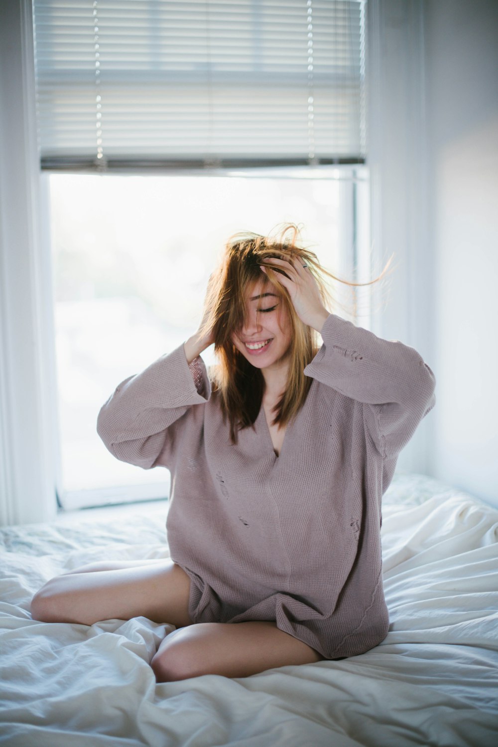 woman in gray long sleeve shirt sitting on bed