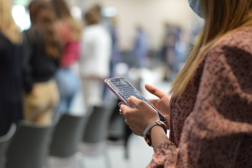 woman in brown and white floral dress holding silver iphone 6