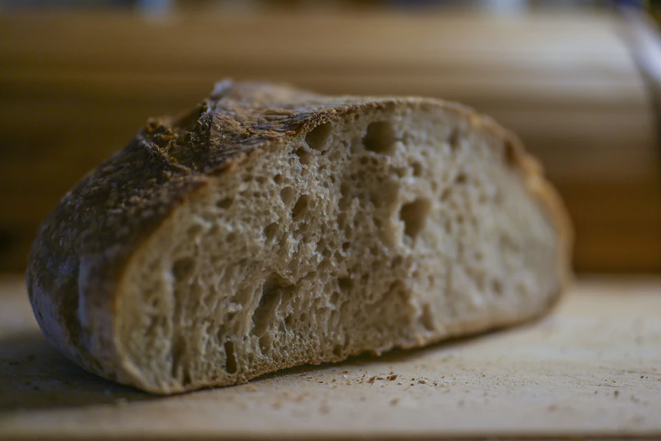 Freshly baked white bread rests on a wooden cutting board on a kitchen counter