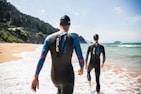 woman in black wetsuit standing on white sand during daytime