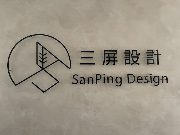 A minimalist logo with a circular geometric design and a stylized tree inside a partial circle. Accompanied by text in both Chinese characters and the English words 'SanPing Design' on a textured gray background.