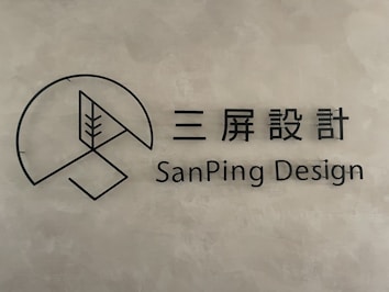 A minimalist logo with a circular geometric design and a stylized tree inside a partial circle. Accompanied by text in both Chinese characters and the English words 'SanPing Design' on a textured gray background.