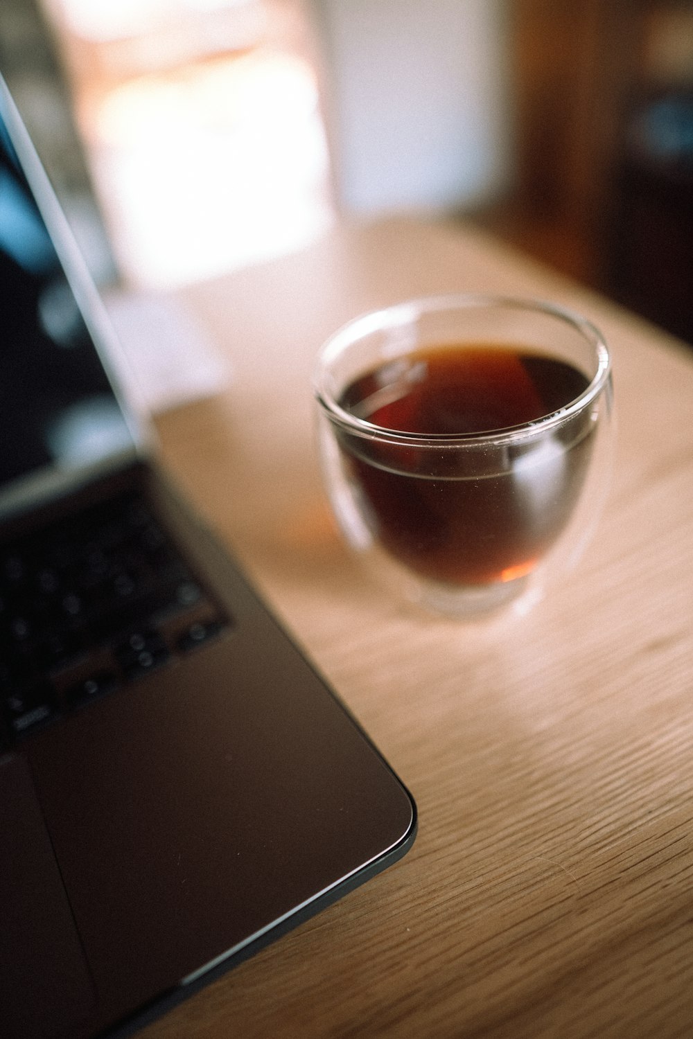 clear drinking glass beside black laptop computer