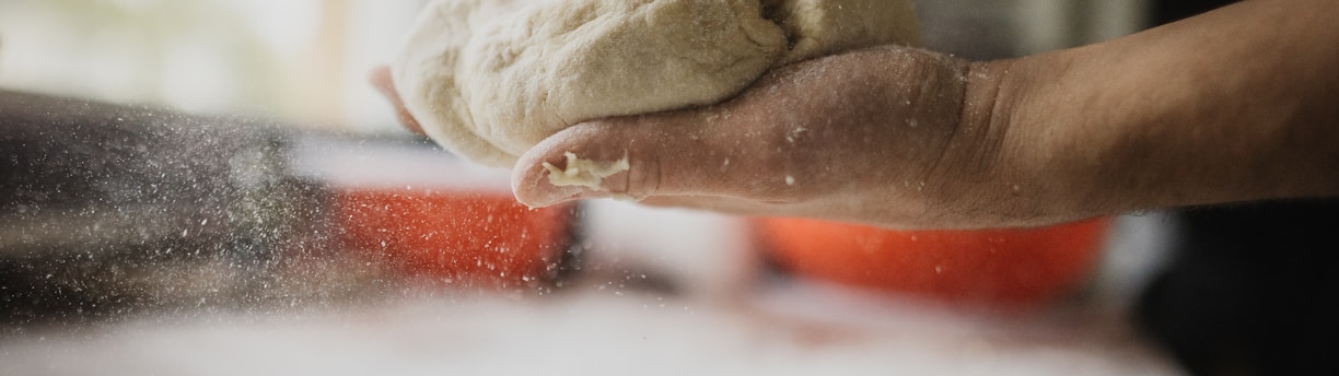 person holding white dough on white table