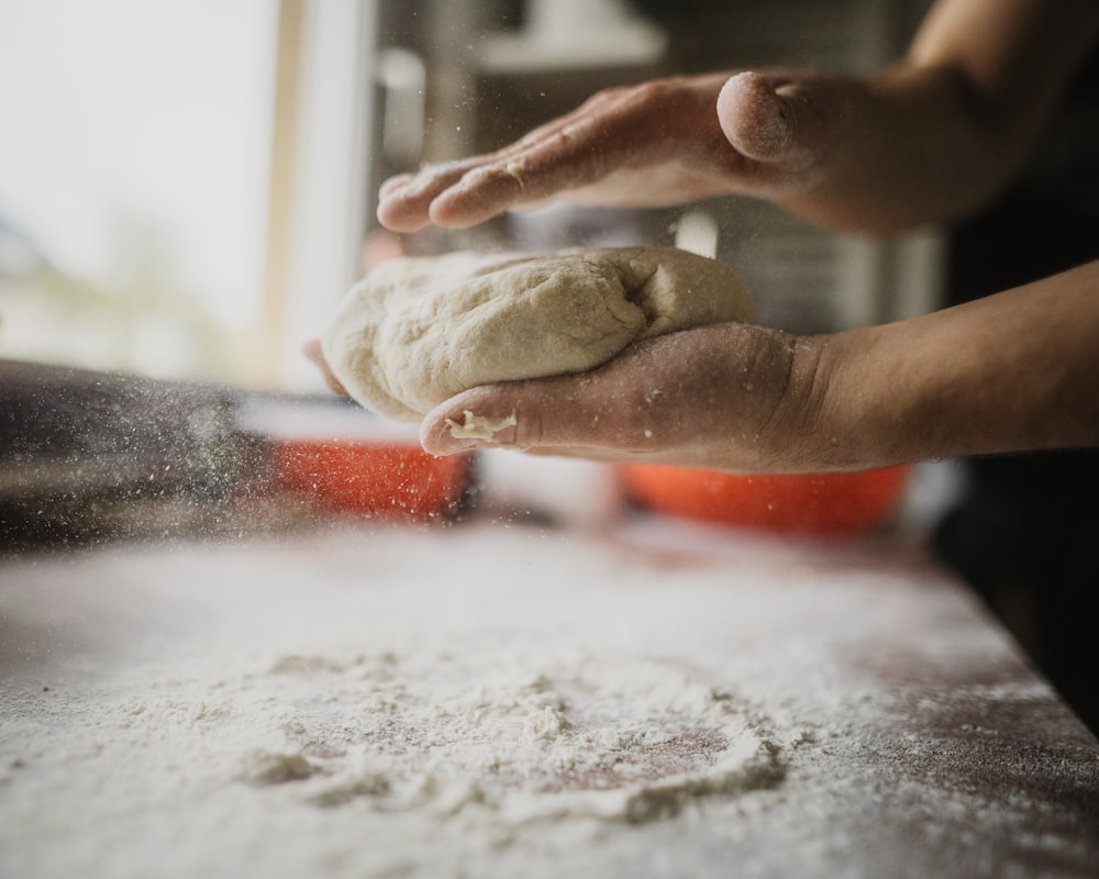 person holding white dough on white table