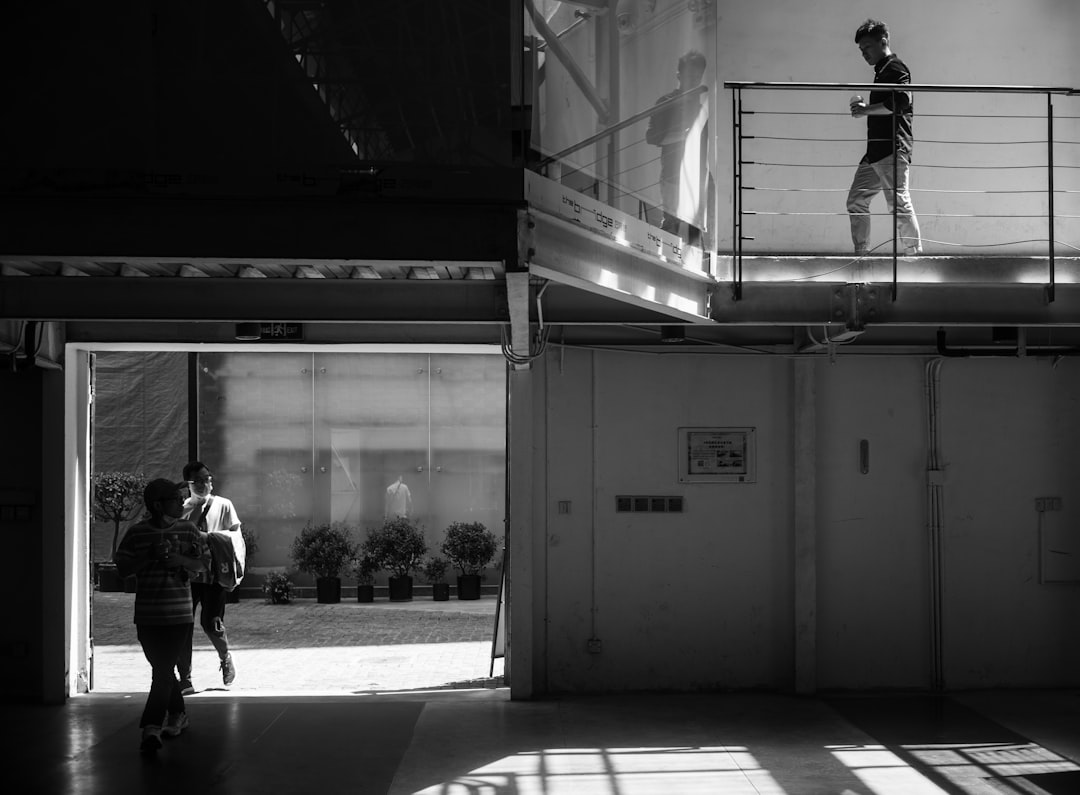 grayscale photo of man walking on sidewalk