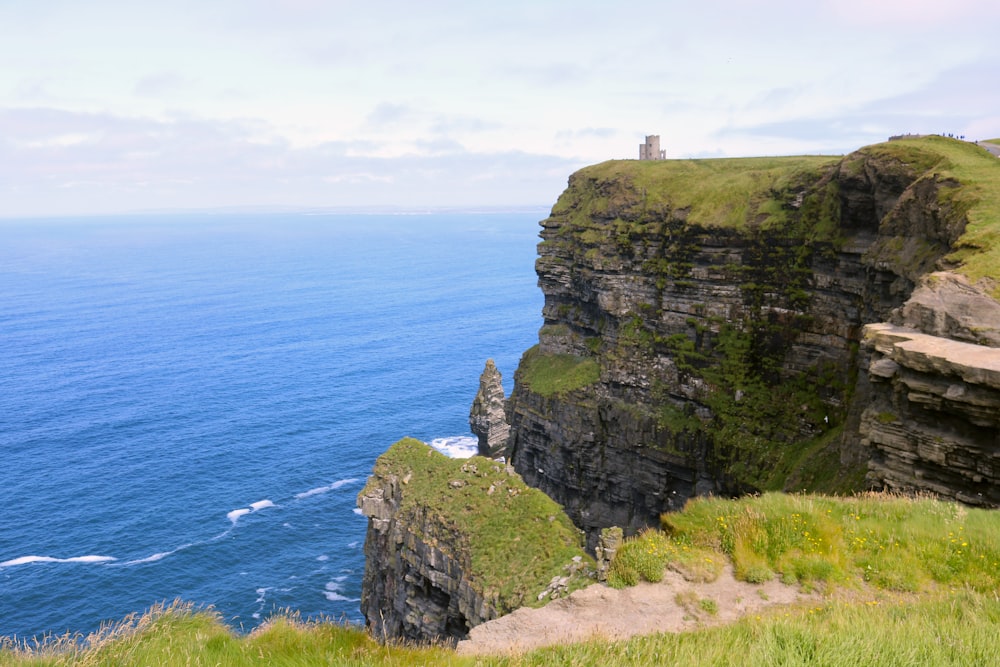 Phare blanc sur la falaise au bord de la mer pendant la journée