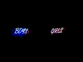 Neon signs reading 'BOYS' in blue and 'GIRLS' in red, symbolizing gender disparities 
