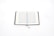 An open book with text on both pages, featuring ornate blue borders. The book is placed on a white background, and a blue bookmark is visible.