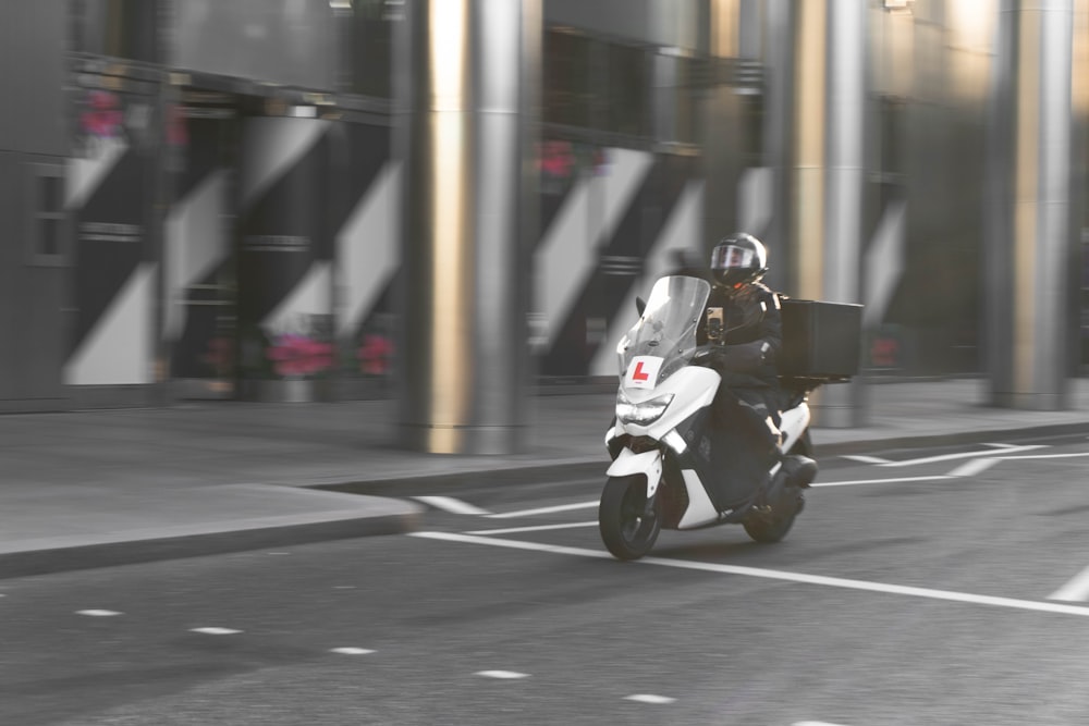 man in black jacket riding white motorcycle on road during daytime