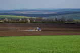 Close-up of a modern tractor working in a green field under a clear blue sky.