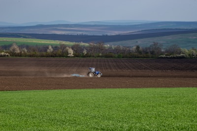 A tractor tilling rich soil under wide open blue skies.