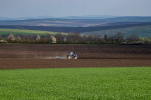 Close-up of a modern tractor working in a green field under a clear blue sky.