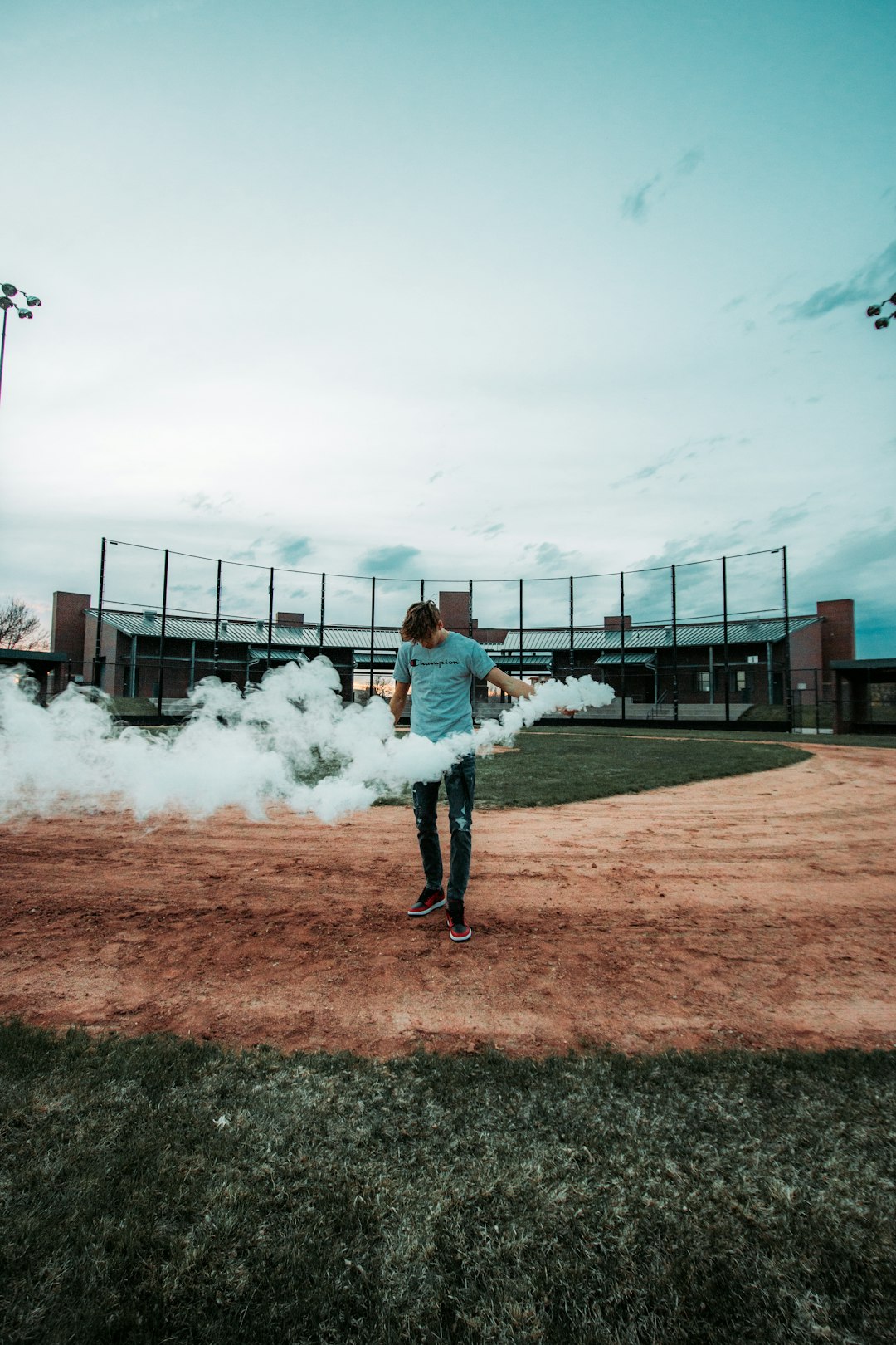 woman in blue denim jacket standing on brown field with white smoke during daytime